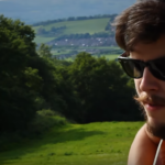 Jon Lilygreen playing his guitar on a hill